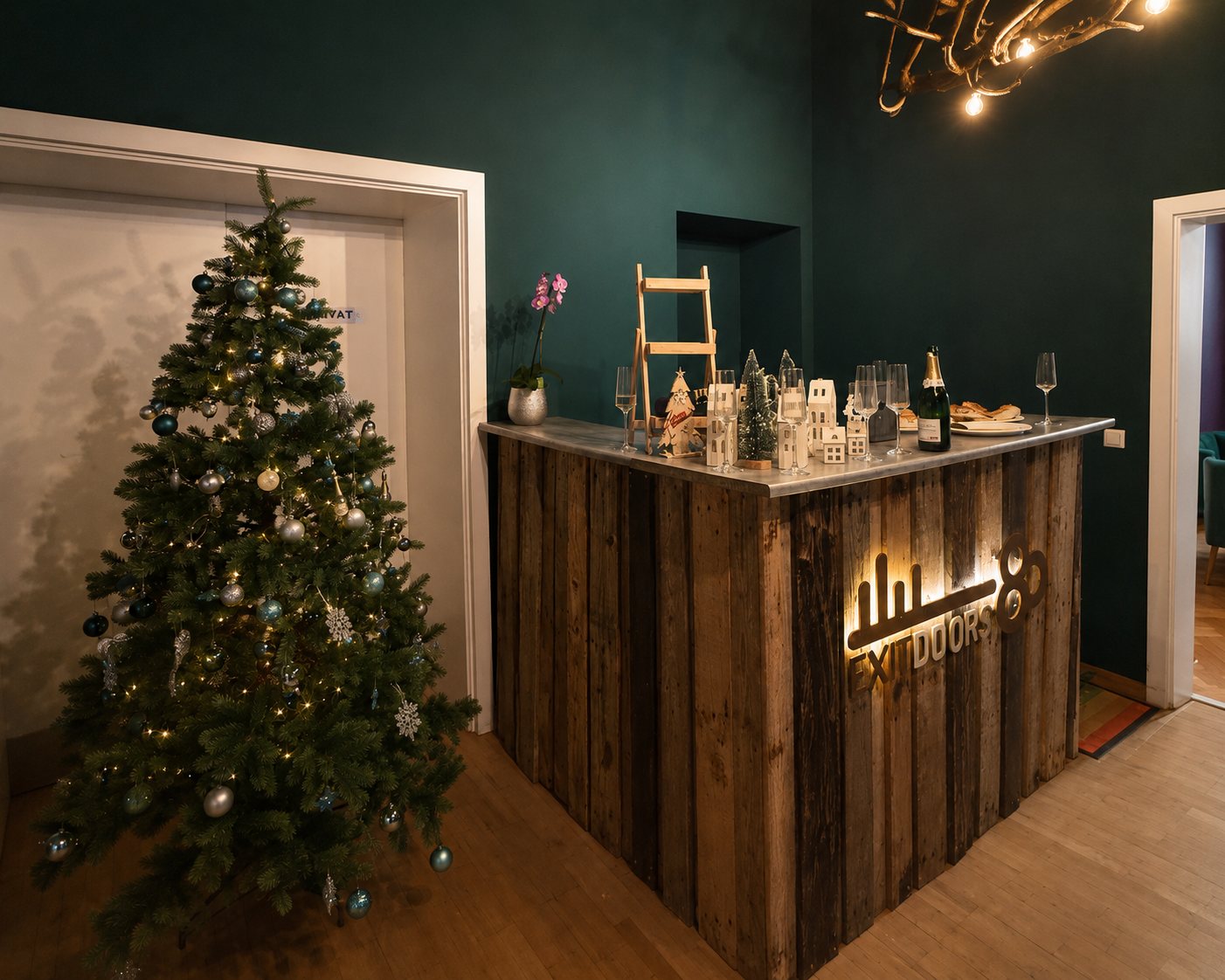 Bar aus Altholz mit beleuchtetem Logo, Sektgläsern und Christbaum im Eingangsbereich